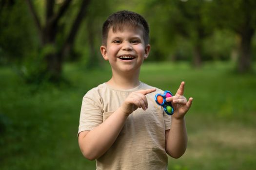 Happy Boy on a Walk in the Suburb. A Cute Boy Spins Spinner. Summer Day With Son. High quality photo