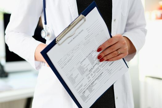 Female doctor hand holding and filling patient history list at clipboard pad during physical. Exam er disease prevention ward round visit check 911 prescribe remedy healthy lifestyle concept.