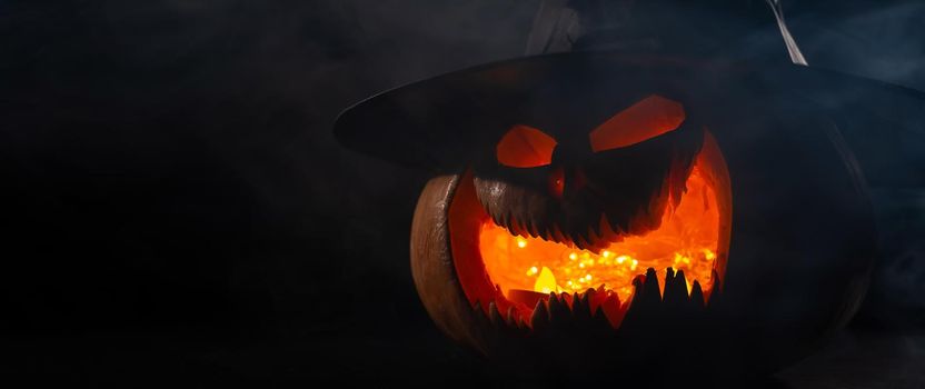 A creepy pumpkin with a carved grimace in the smoke. Jack o lantern in the dark