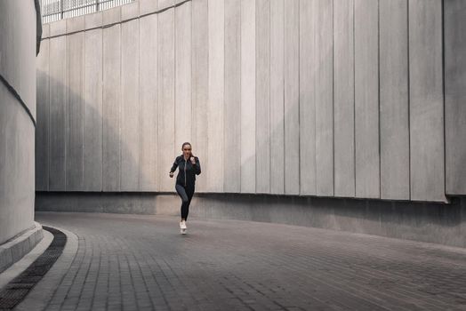 Runner athlete is running near the stadium. Woman jogging workout wellness concept.