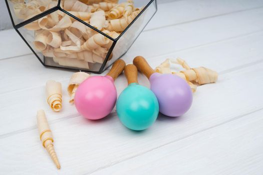 Children's wooden maracas are on a white table. Pink, lilac and mint maracas. Bright toys for children made of natural wood. Zero waste.