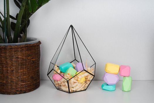 Children's wooden constructors in a glass florarium. Colored cubes of various shapes.
