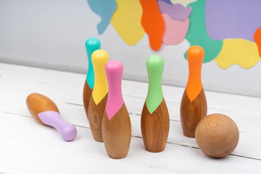 Skittles and a ball made of natural material. Bowling for children made of wood. Set for bowling. Children's wooden toys. Bright background.