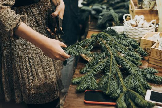 Master class on creating a Christmas wreath with your own hands. Decoration for the house for Christmas. Woman making christmas wreath. Creating a Christmas wreath of spruce branches.