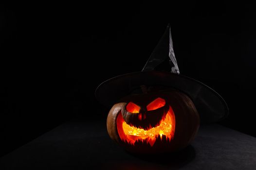 Glowing pumpkin in a witch hat in the dark. Jack o lantern