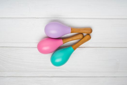 Children's wooden maracas are on a white table. Pink, lilac and mint maracas. Bright toys for children made of natural wood. Zero waste.