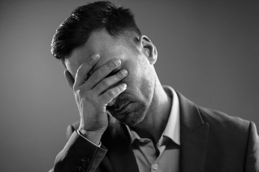 Tired Businessman After a Hard Day. Office Manager Touching His Face. Boss is Disappointed. Black and White Portrait. High quality photo