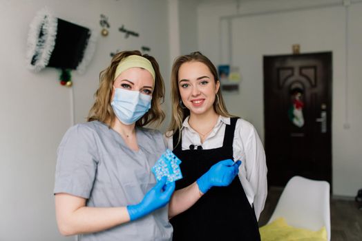 Manicurist wearing protective mask painting female nails with nail polish in manicure salon.