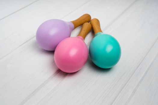 Children's wooden maracas are on a white table. Pink, lilac and mint maracas. Bright toys for children made of natural wood. Zero waste.