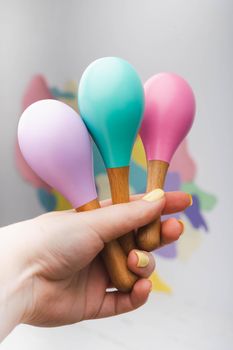 Baby maracas in hand with yellow manicure. Bright wooden rattles for kids. Toys made of natural wood.