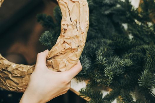 Woman making christmas wreath. Master class on creating a Christmas wreath with your own hands from natural fir. Craft paper. Concept of florist's work before christmas holidays.