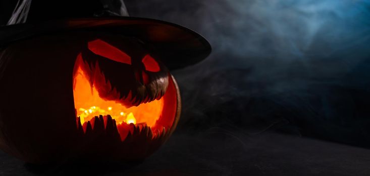 A creepy pumpkin with a carved grimace in the smoke. Jack o lantern in the dark