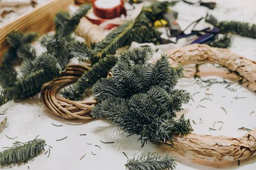 Creating a Christmas wreath of spruce branches and a cardboard frame. Craft paper. Decoration for the house for Christmas. Concept of florist's work before christmas holidays.