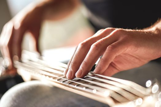 Feeling my instrument...Close-up of male hands touching metal strings of guitar. Musical instruments. Music concept. Creativity