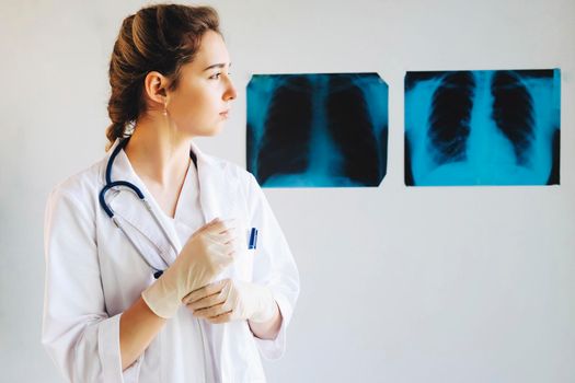 Female doctor at work in public medical clinic and examining x-ray plates of lungs. The girl doctor works on the front line. Radiologist woman checking x-ray, medical and radiology concept.