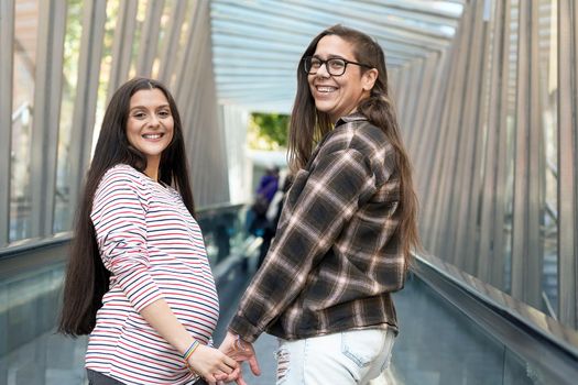 Close up of Lesbian Pregnant Couple holding hands outdoors. High quality photo