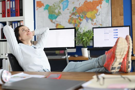 Beautiful joyful woman in the office daydreaming and looking at the ceiling, procrastination. Employee resting at workplace