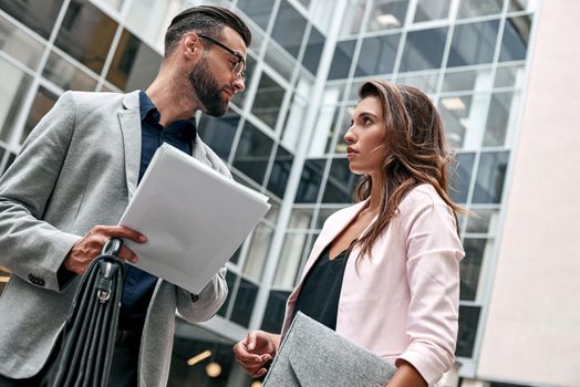 Preparation for meeting. Two young business people standing outside on the city street holding documents looking at each other smiling happy bottom view close-up