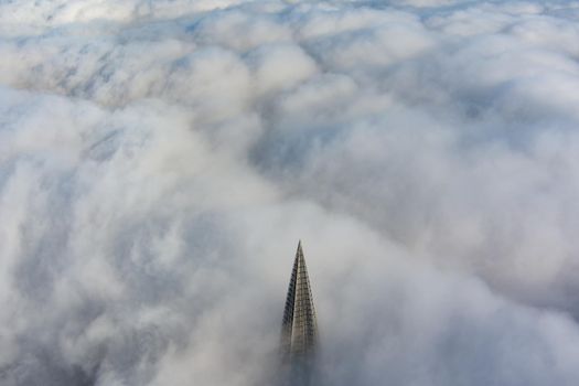 Russia, St. Petersburg, 14 October 2021: The top of the tallest skyscraper in Europe above the clouds, the building of the Gazprom oil company, the spire of a metal and glass structure. High quality photo