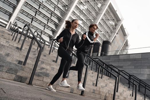 Early morning workout. Young couple running downstairs near the football stadium. Living healthy lifestyle.