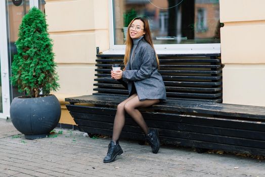 Beautiful young chinese student holding a cup of coffee in the street