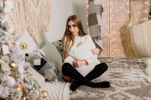 Happy young lady with long hair near fireplace and the Christmas tree, gifts. New year concept.