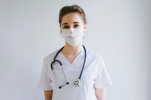 Doctor in a protective disposable mask on his face. A girl in a doctor's uniform. Photo on a medical topic. International Doctor's Day.