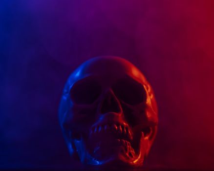 Human skull in pink and blue smoke on a black background. Halloween