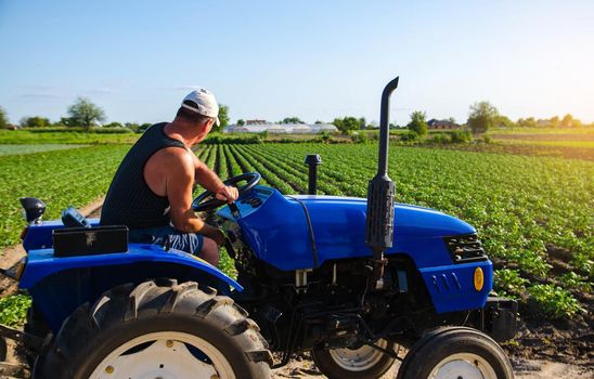 Farmer works in the field with a tractor. Agroindustry and agribusiness. Farm machinery. Crop care, soil quality improvement. Plowing and loosening ground. Field work cultivation. Farming landscape