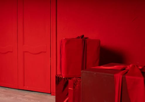 Big wrapped gifts near red wall. Boxes of presents on red background. Concept of holidays and surprises