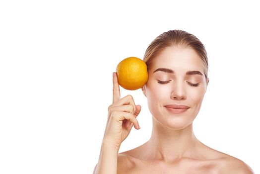 Beautiful womans face with orange close up studio photo on white background. Light hair, grey eyes, closed eyes