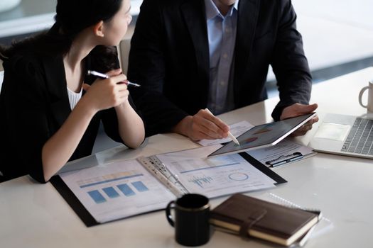 Close up of business people discussing a financial plan with paperwork and digital tablet.