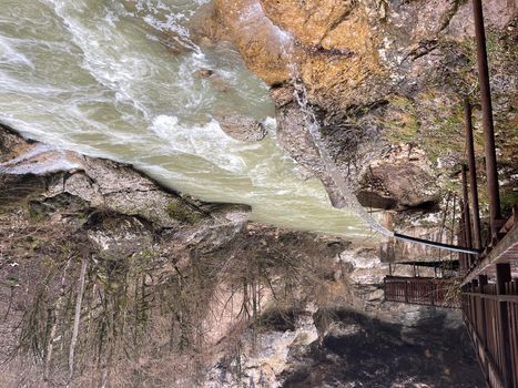 Rain water flowing from drainpipe to mountain river. Rain water flows down from downspout on background of mountain landscape