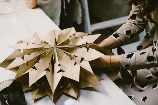 The origami stage. DIY personalized xmas decoration. Creating hand made christmas ornaments. Step by step instructions. Snowflake or three-dimensional star made of kraft paper.