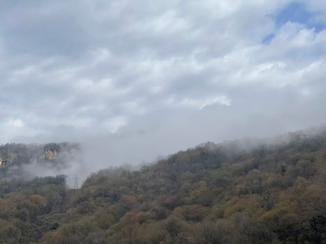 Beautiful landscape of mountainous terrain in fog. Nature background of hilly area in foggy and cloudy weather