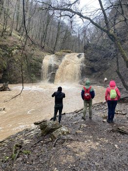 Beautiful landscape of powerful muddy waterfall in mountainous terrain. Dirty mountain waterway flows down and splashes