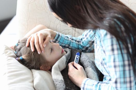 Caring mother touches the forehead of a sick girl, close-up. Temperature measurement in a girl, pademia covid