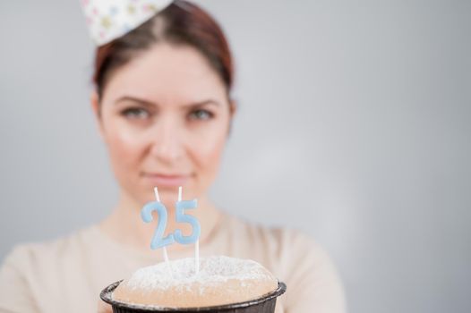 The happy woman makes a wish and blows out the candles on the 25th birthday cake. Girl celebrating birthday