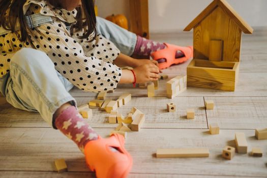 Wooden children's construction kit. Toys made of eco-friendly material. The castle is made of wooden cubes. Children's room. Eco-toys. The girl builds a tower out of a wooden construction kit.