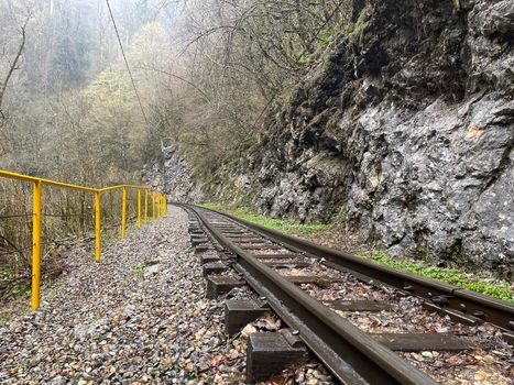 Close up of railway in mountainous terrain. Railway track in rainy weather in amazing and mysterious nature