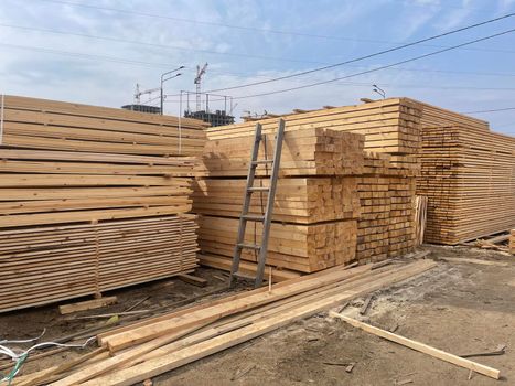 Wooden boards, lumber, industrial wood, timber. Pine wood timber stack of natural rough wooden boards on building site. Industrial timber building materials.