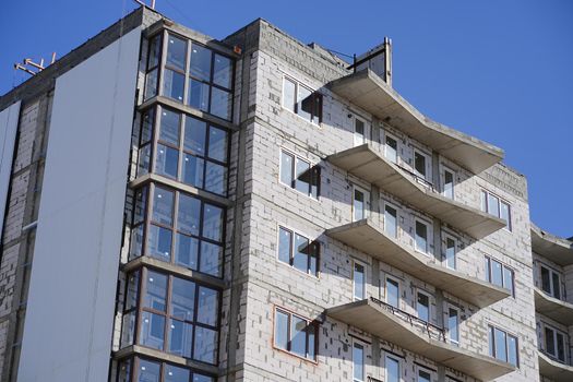 Close up of construction residential building on background of blue sky. New construction of brick house in sunny weather