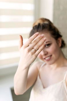 Beautiful excited young woman wearing dress standing showing engagement ring on her finger