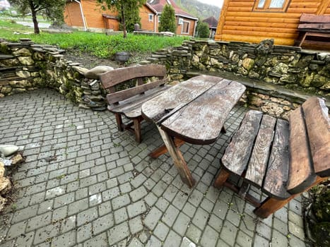 Close up of wooden table with benches in countryside. Log table and benches in empty village in cloudy weather