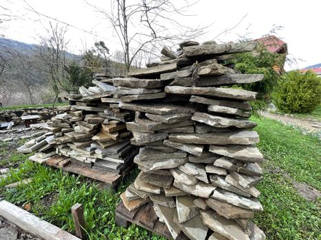 Pile of building materials on street in countryside. Close up of stone tiles on ground outdoor. Concept of constructing sidewalk