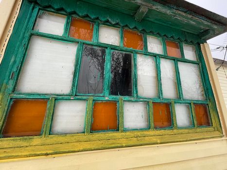 An old wooden window with multicolored panes. Multicolored glass panels on the antique window.