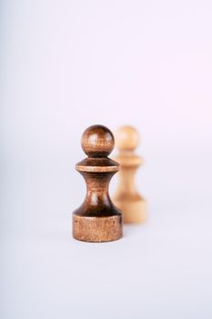 Close up of rows of black and white wooden chess pieces on white background. Selective focus on black pawns