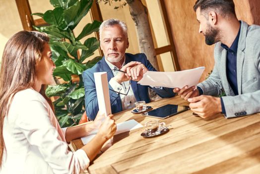 Business lunch. Three people in the restaurant sitting at table discussing project concentrated. Team work concept