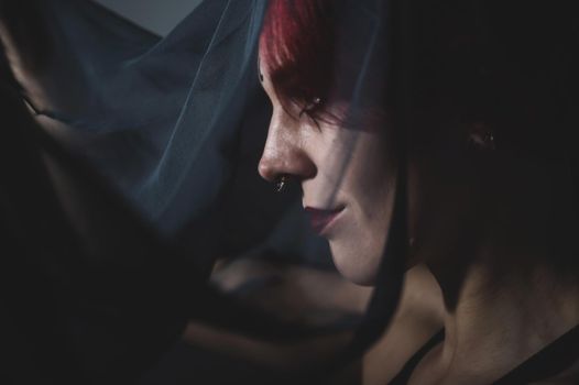 Profile of a woman in a black veil. Costume Dead bride for Halloween. Portrait of an evil grinning Witch in front of a coven