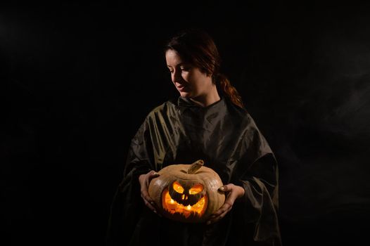 Caucasian woman holding pumpkin in the dark.